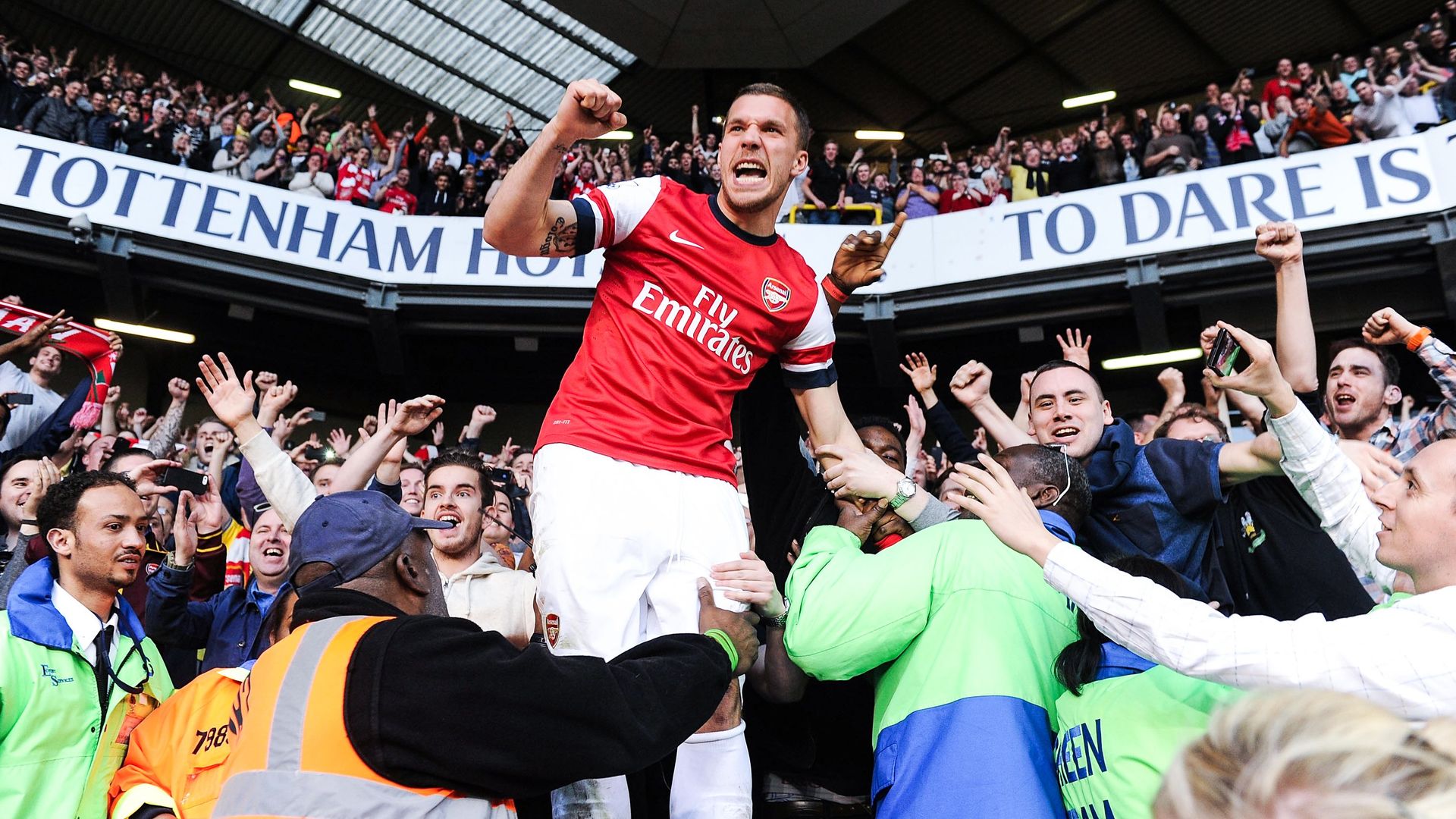 Lukas Podolski jumps into the crowd and is mobbed by jubilant Arsenal fans