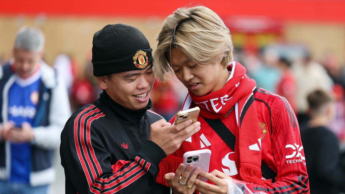 Two Man Utd fans look at their phones