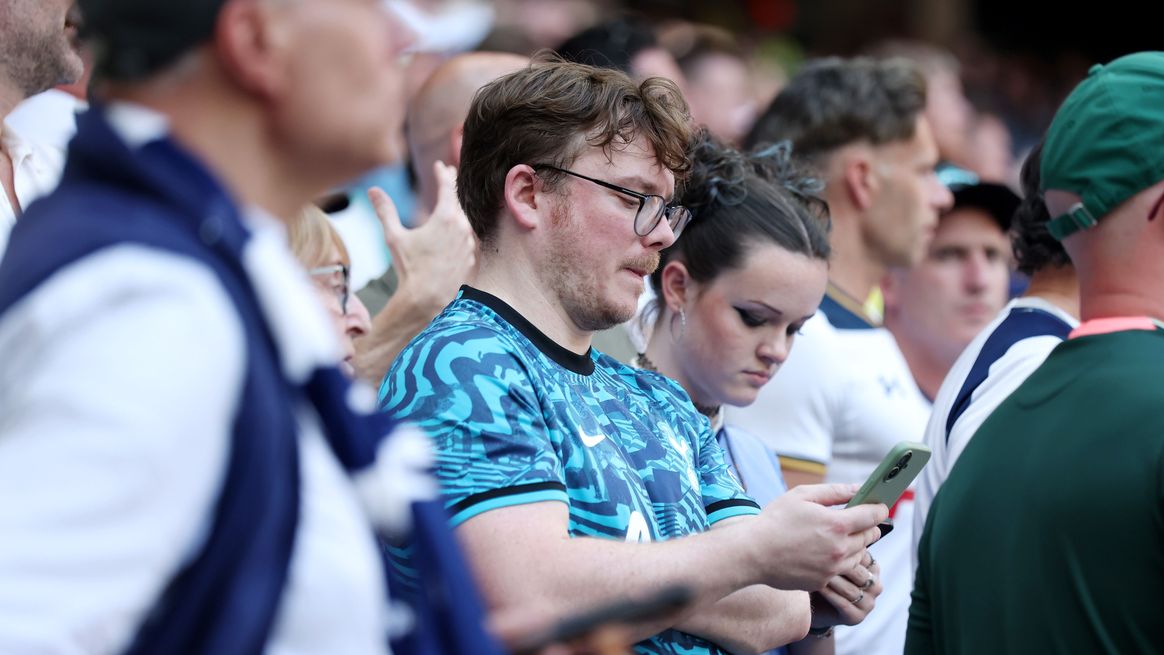 A Spurs fan looks at his phone